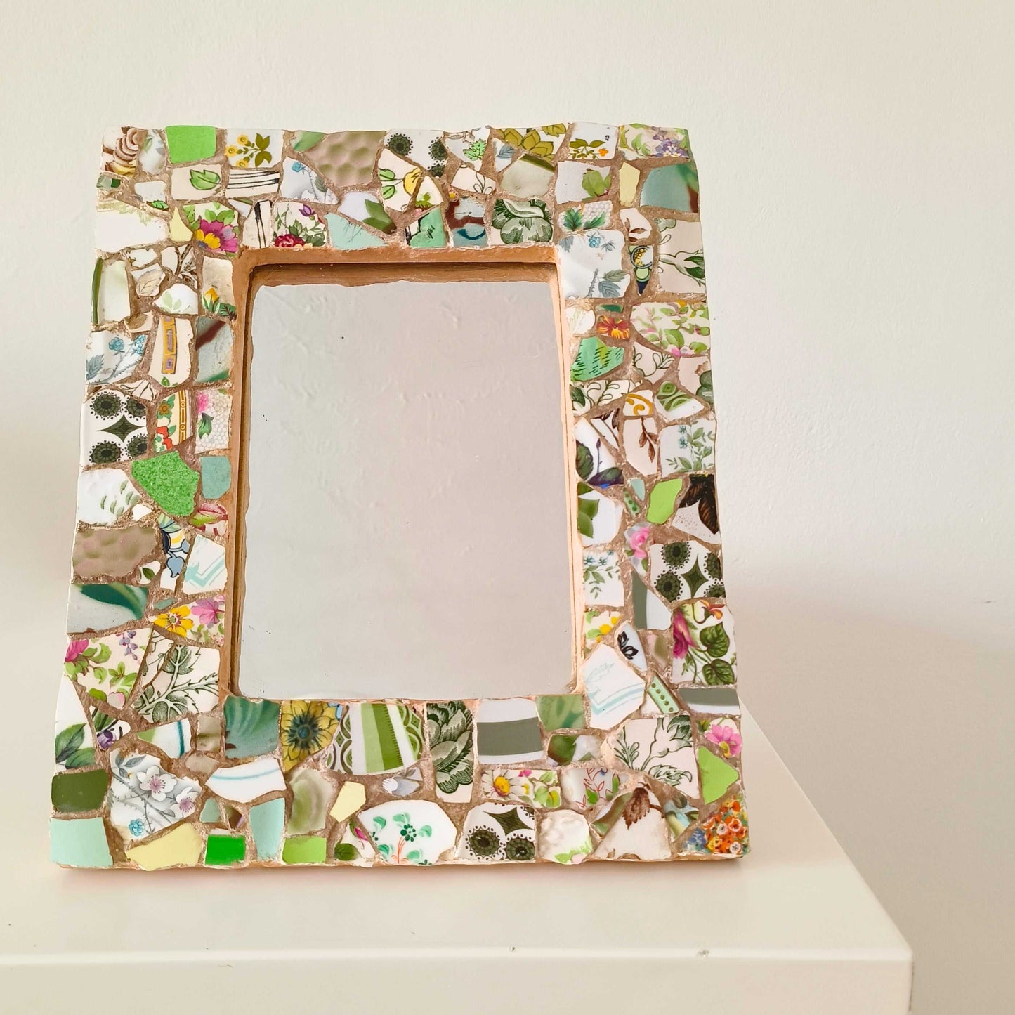 Vintage mosaic picture frame with ceramic and tile fragments in soft greens and botanical motifs