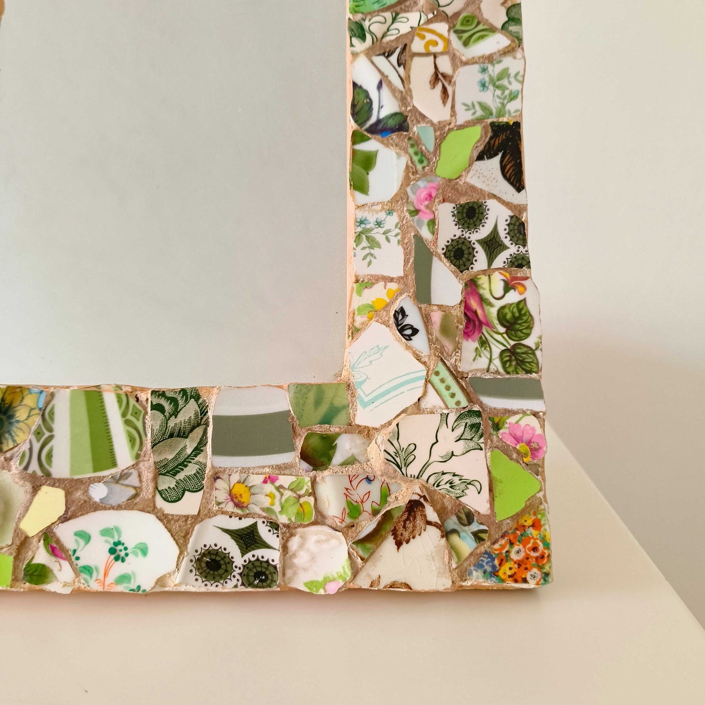 Vintage mosaic picture frame with ceramic and tile fragments in soft greens and botanical motifs