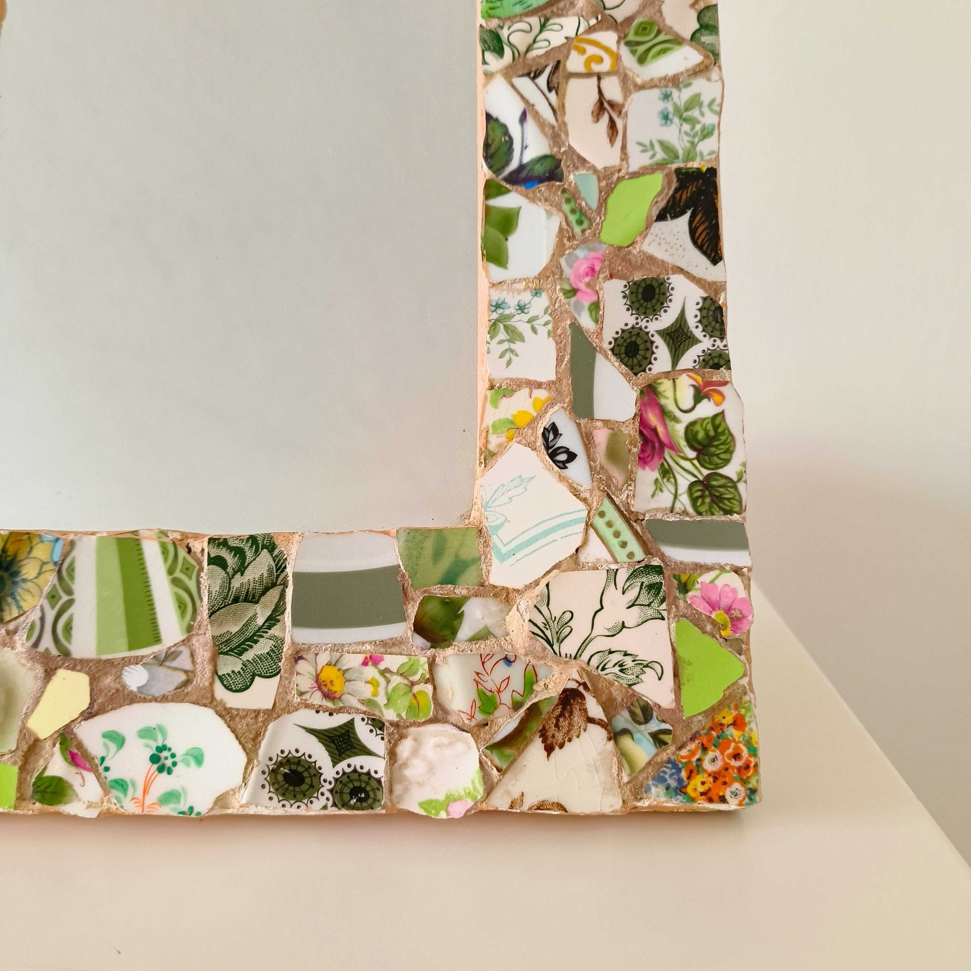 Vintage mosaic picture frame with ceramic and tile fragments in soft greens and botanical motifs