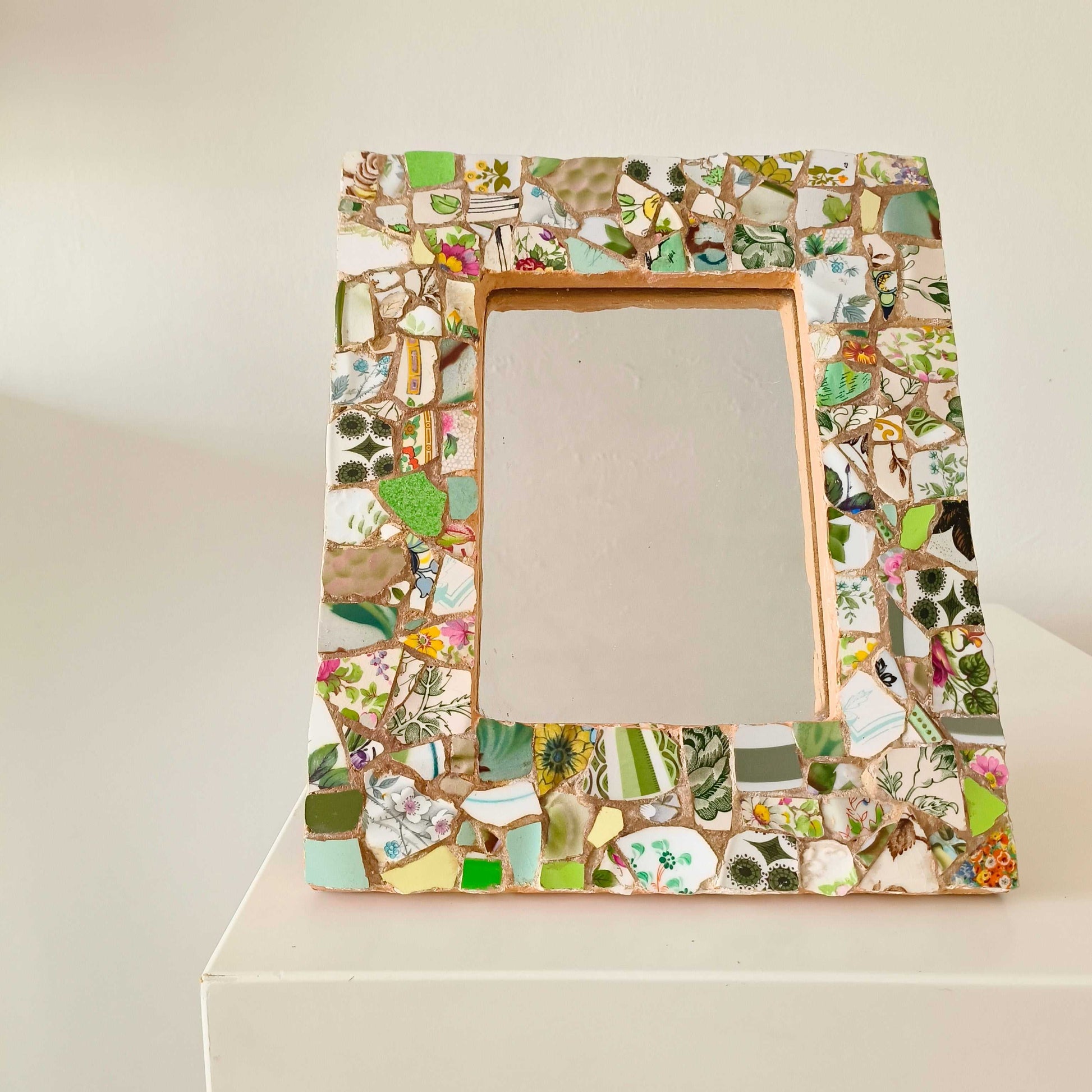 Vintage mosaic picture frame with ceramic and tile fragments in soft greens and botanical motifs