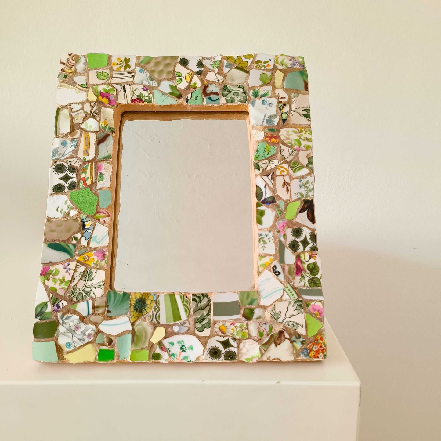 Vintage mosaic picture frame with ceramic and tile fragments in soft greens and botanical motifs
